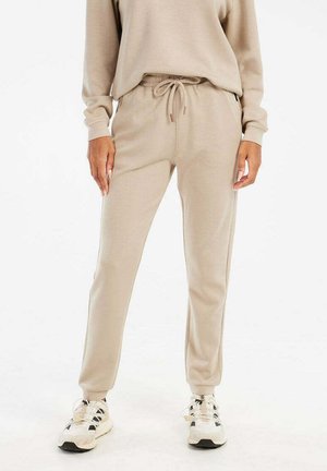 Pantalons jogger beige avec une taille élastique et un cordon de serrage. Fabriqués dans un matériau doux, avec des poches latérales et un design de jambes fuselées.