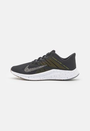 Scarpa da corsa grigio scuro con suola bianca maculata, swoosh Nike multicolore glitterato e testo giallo sul lato con la scritta "Engineered for Speed."