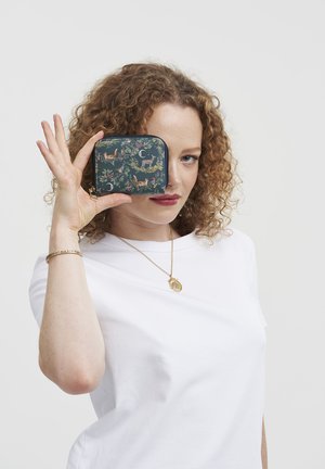 Coin purse with a dark green fabric featuring a wildlife pattern of deer and foxes, zip closure, and gold hardware accents.