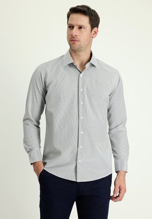 Camisa de botón gris claro con un sutil patrón de rayas, mangas largas y cuello puntiagudo, combinada con pantalones oscuros de color navy.