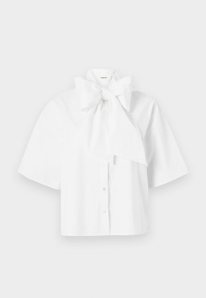 White short-sleeve blouse with a large bow detail at the collar, featuring a button-up front and a smooth, structured fabric.