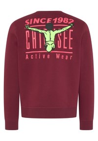 Sudadera burdeos de manga larga con puños acanalados. Presenta un gran gráfico en rosa y verde en la parte trasera, incluyendo texto y una figura.