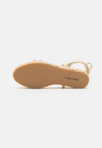 Beige sandaler med texturerad vävd överdel och ankelrem. Sula i gummi med en ljusbrun färg och lätt greppstruktur. Storlek 37.
