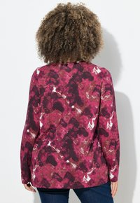Langärmliges Oberteil mit einem abstrakten Muster in Rosa und Burgunder, mit lockerem Schnitt und leicht gekurvtem Saum. Hergestellt aus weichem Stoff.