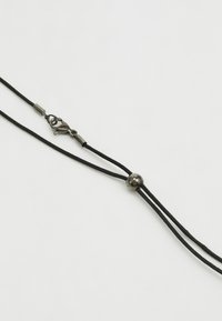 Svart snorhalskjede med metallspenne og kulejustering. Har en teksturert overflate og skinnende metallakenter. Justerbar lengde.