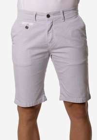 Pantalones cortos ajustados para hombre en gris claro con cierre de botón y cremallera, presillas para cinturón y bolsillos delanteros y traseros, usados por una persona.