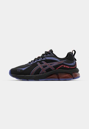 Scarpe sportive nere con una parte superiore texturizzata, accenti viola e rossi, suola curvata con un'unità d'aria visibile e modelli di battistrada pronunciati.