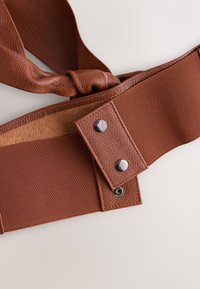 Brown leather belt featuring a textured finish, satin fabric, metal hardware, and a knotted design with fastening details.