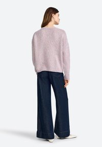 Lichtroze gebreide sweater met een textuurpatroon, oversized pasvorm, ronde halslijn, gecombineerd met wijduitlopende donkerblauwe denim broek.