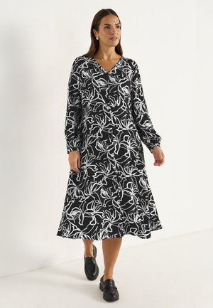 Schwarzes Kleid mit weißem Blumenmuster, langen Ärmeln, V-Ausschnitt und kniefrohem Rock. Aus glattem Stoff gefertigt, mit einem klassischen, fließenden Design.