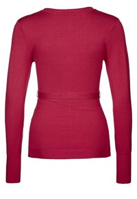 Tiukka, pitkähihainen paita kirkkaan vaaleanpunaisesta neuloksesta, jossa pyöreä kaula-aukko ja kiristetty vyötärö joustavalla nauhalla.