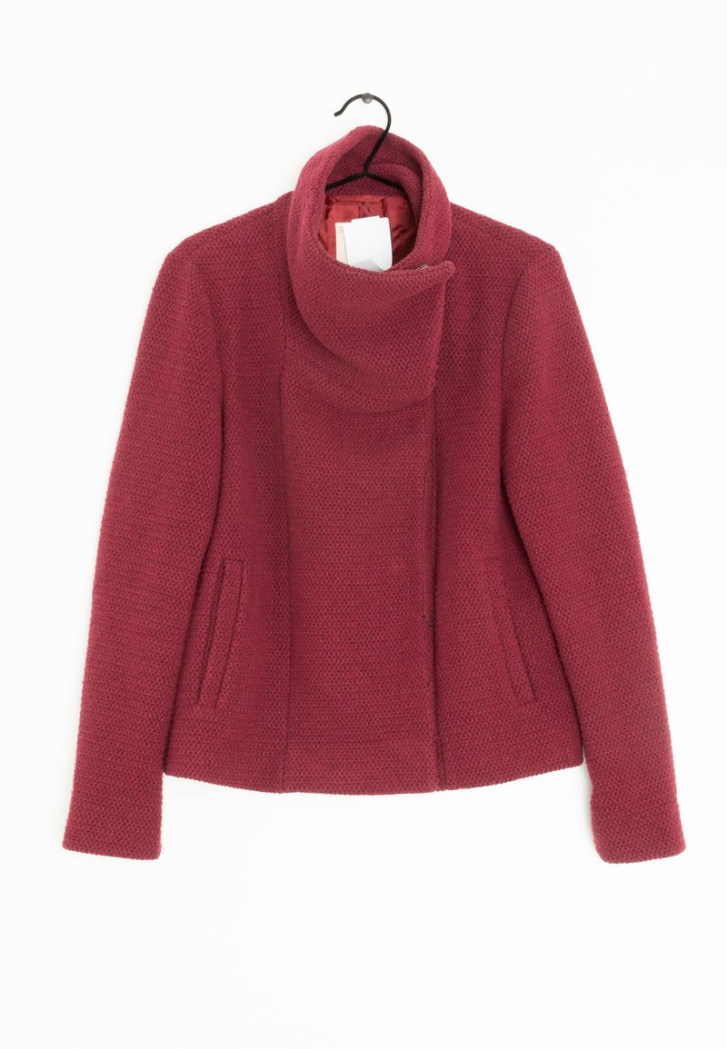 Punainen teksturoitu takki, jossa on korkea kaulus, kaksi sivutaskua ja pitkät hihat, suunniteltu puhtaalla siluetilla ja pehmeästä kankaasta.