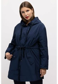 Tummansininen hupparitakki, jossa on kiristettävä vyötärö, napitus ja kaksi sivutaskua. Materiaaliltaan kevyt ja sileä.