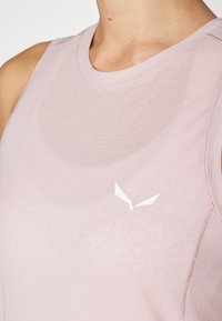 Light pink athletic tank top made of soft fabric, featuring a round neckline and a small white logo on the chest area.