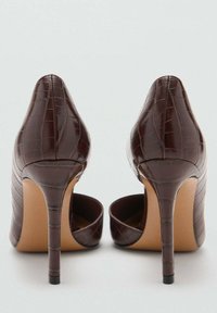 Scarpe con tacco alto in pelle sintetica color marrone con effetto coccodrillo, con punta affusolata e finitura testurizzata. Presentano un sottile tacco a stiletto e un design aperto sul retro.