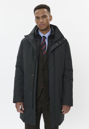 Schwarzer Außemantel mit hohem Kragen, über einem dunklen Anzug und einer gestreiften Krawatte getragen. Verfügt über einen Reißverschluss und Druckknopfverschluss, mit glatter Textur.