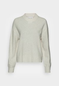 Pull oversize beige clair en tissu doux, doté d'un col rond, d'un ourlet côtelé et de manches longues tombantes pour une coupe décontractée.