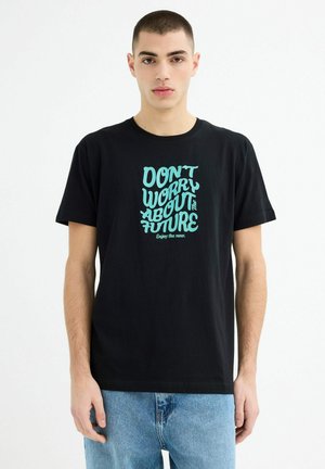 Camiseta de algodón negra con texto en verde menta que dice "NO TE PREOCUPES POR EL FUTURO" en una tipografía divertida. Ajuste casual y diseño de cuello redondo.