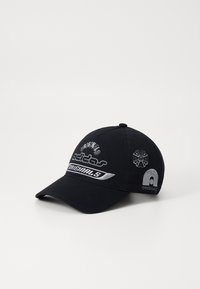 Črna bejzbol kapa z vezenim logotipom "adidas Originals", srebrnimi detajli, ukrivljenim robom in kontrastnim šivom. Mehka tkanina.