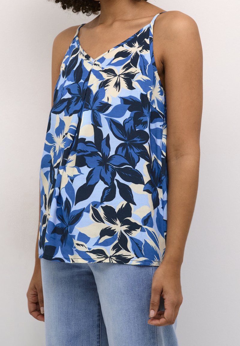 Débardeur bleu à fleurs avec un décolleté en V, présentant de grandes fleurs noires et crème sur un fond bleu clair. Tissu doux avec une coupe décontractée.