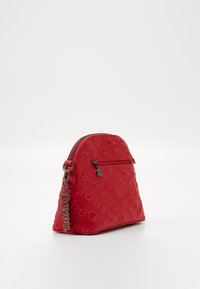 Sac zippé rouge en forme de triangle, en matériau texturé avec le nom de la marque embossé, et une chaîne détachable avec une étiquette "BeYou".