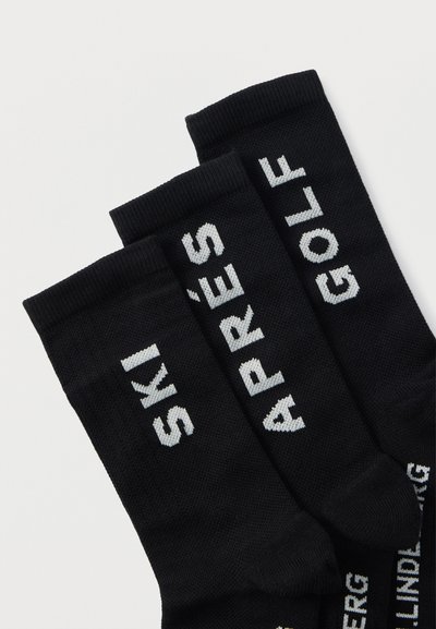 Calzini neri in misto cotone, con testo bianco ricamato: "SKI", "APRÈS" e "GOLF" su tre paia separate.