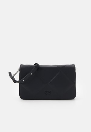 Sac bandoulière en cuir matelassé noir avec sangle réglable et logo "CK" subtil sur le devant.