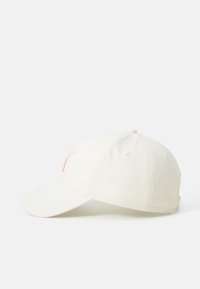Boné de algodão branco com aba curva e uma letra "K" bordada em vermelho na frente. Possui ilhoses para ventilação e uma fita ajustável.