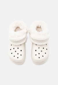 Fehér klumpák puha, műszőrme béléssel, több kör alakú szellőzőnyílással, lekerekített orral és mintázott talppal.
