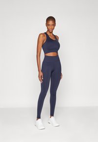 Navy atletisk crop top og leggings sett laget av elastisk stoff; har en scoop hals, matchende høy midjebånd og minimal søm.