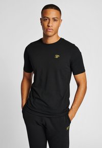 Svart kortärmad t-shirt av bomull med en liten gul broderad logotyp på bröstet. Enkelt omlottkrage-design.