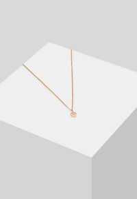 Náhrdelník z ružového zlata s jemným reťazcom a pendantom v tvare kvetu, ktorý má v strede priehľadný drahokam. Hladký povrch a minimalistický dizajn.