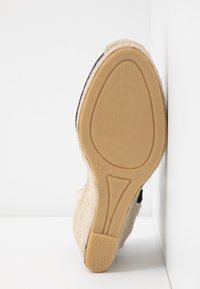 Semelle d'une espadrille compensée beige avec semelle en caoutchouc, taille 37, présentant un talon texturé et des détails en corde autour du bord.