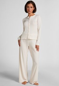 Cream ribbed knit loungewear set featuring a long-sleeve button-up top and wide-leg pants, both with a soft texture and relaxed fit.
