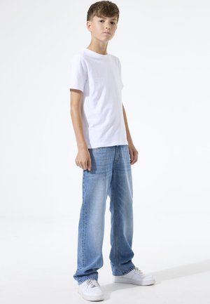 Wit T-shirt met korte mouwen en een ronde hals, gecombineerd met lichtblauwe jeans met rechte pijpen en witte sneakers. Eenvoudig en klassiek ontwerp.