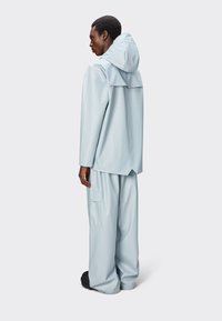 Impermeable azul claro con capucha, con un corte relajado, mangas largas y grandes bolsillos. Fabricado con material suave y a prueba de agua.