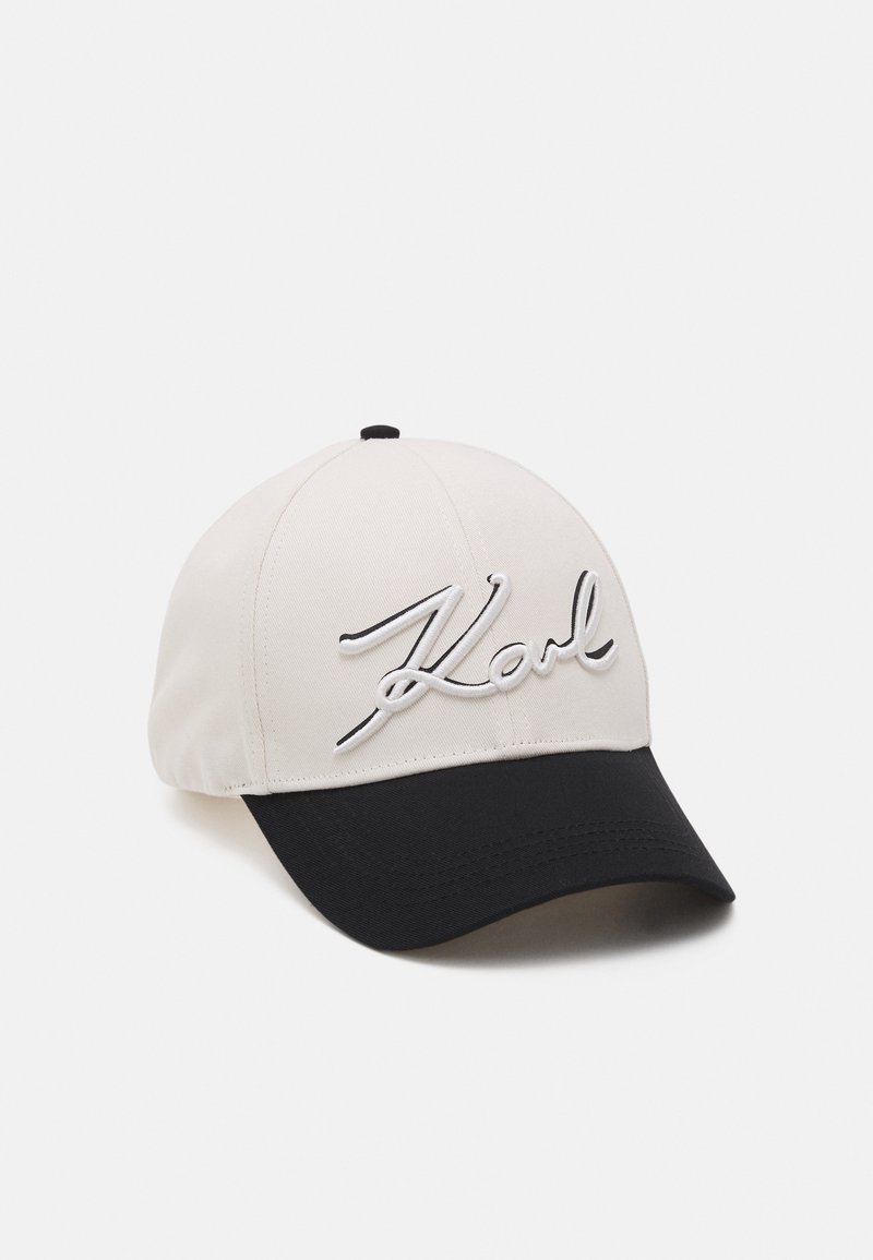 Casquette de baseball avec une calotte blanche et une visière noire, comportant le mot "Karl" brodé en écriture cursive blanche sur le panneau avant.