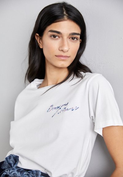 Weißes Baumwoll-T-Shirt mit lockerer Passform. Verfügt über gestickten Text in Blau und Lila. Kurze Ärmel und runder Ausschnitt.