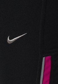 Černé sportovní legíny s stříbrným logem Nike, růžovými bočními akcenty a kontrastním prošitím, vyrobené z elastické strukturované látky.