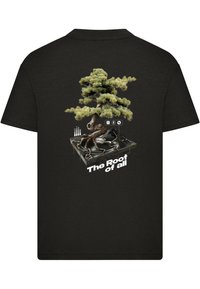 Juodas marškinėliai su bonsai medžio grafika, augančiu iš plokštelės grotuvo, ir užrašu "Visų šaknys" ryškiomis baltomis raidėmis.