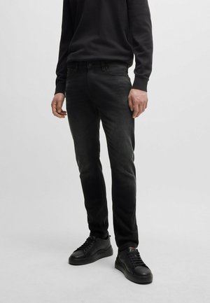 Musta farkut slim fit -tyyliin haalistuneella designilla, yhdistettyinä mustiin lenkkareihin. Kankaan pinta on sileä ja näkyvät saumat minimissä.