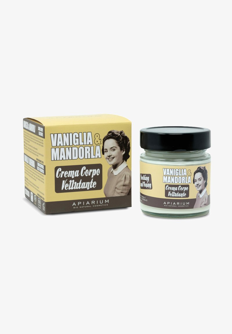 Crema corpo Vaniglia & Mandorla in un barattolo di vetro trasparente con coperchio nero, presentata accanto a una scatola gialla con grafiche in stile vintage.