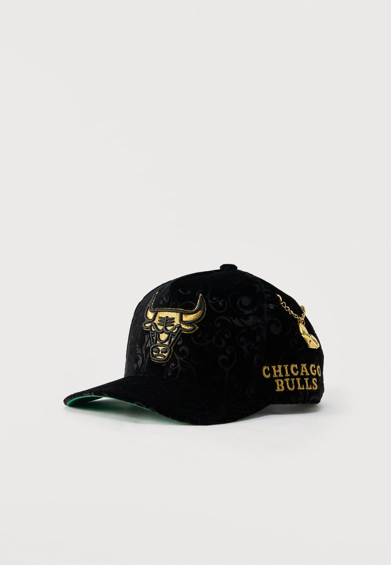 Schwarze Chicago Bulls Kappe mit goldenem Stier-Logo vorne, goldenem "CHICAGO BULLS" Schriftzug an der Seite und einem kleinen goldenen Kettenanhänger.