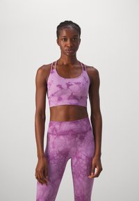 Violet sportinis liemenėlis ir legginai, su dažytų audiniu, be siūlių dizainu, reguliuojamomis petnešėlėmis ir tekstūruota medžiaga.