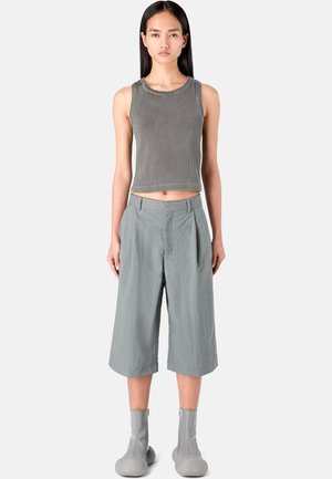Top corto de punto gris con acanalado, combinado con culottes sueltos de color gris claro. El modelo lleva botas gris medio-calentador con cremalleras y punteras redondeadas.