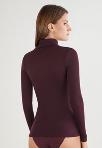 Langarm-Pullover mit Rollkragen in dunklem Burgunderrot, geripptem Textur, tailliertem Design, mit einem hohen Kragen und nahtlosen Schultern.