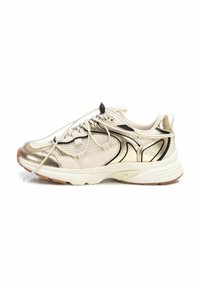 Zapatilla beige con acentos metálicos dorados, paneles de malla y detalles en negro. Cuenta con una suela blanca gruesa y cordones planos.
