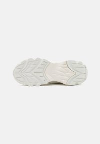 White sneaker sole with textured rubber for grip, featuring a wavy pattern and reinforced areas for durability and support.