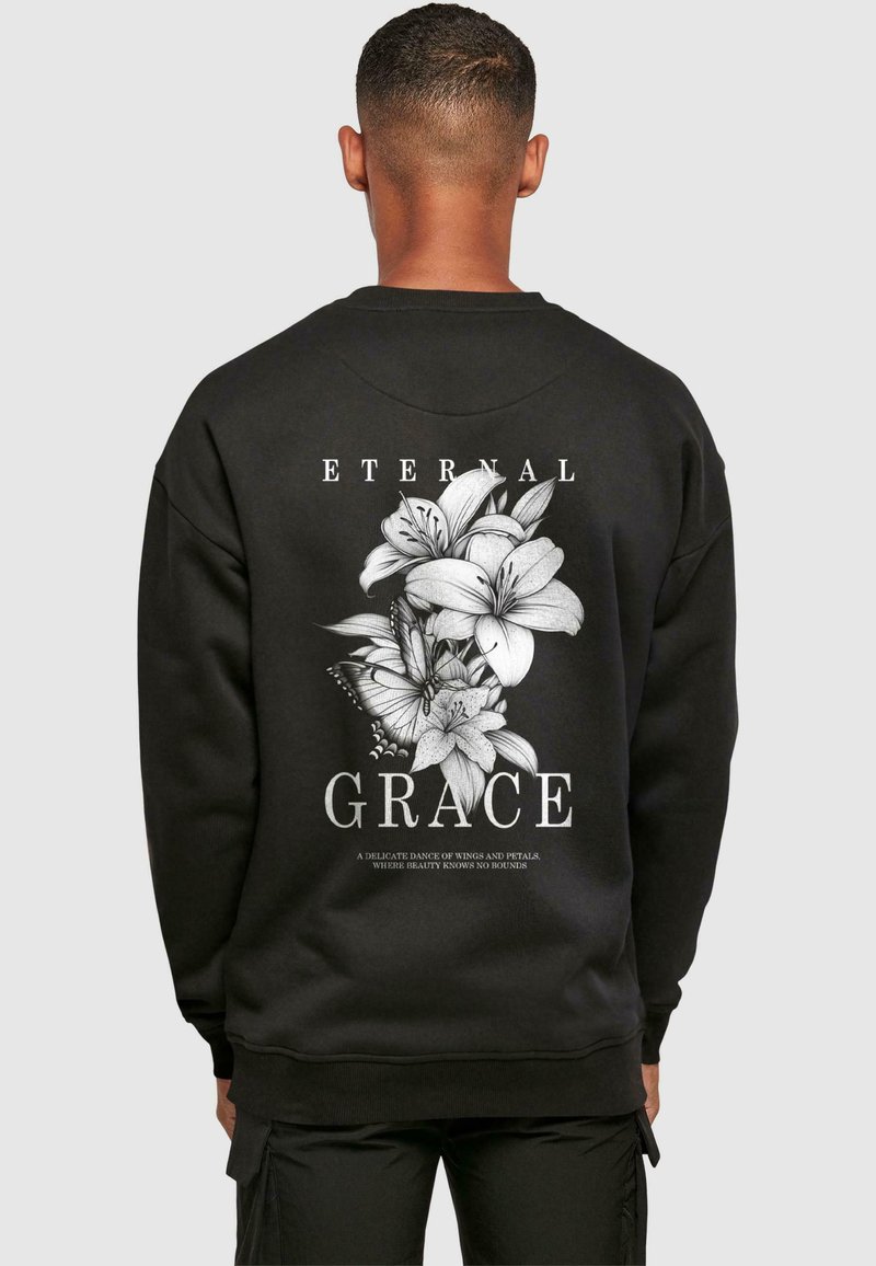 Black sweatshirt featuring a large white floral design on the back with the text "ETERNAL GRACE" above and below the graphic.
