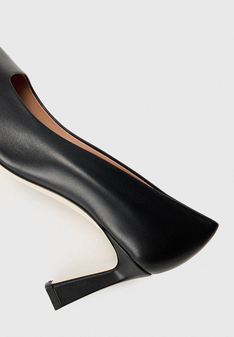 Czarne szpilki wykonane z gładkiej skóry, z wycięciem na palce i smukłym, szpiczastym noskiem. Wyróżniają się elegancką sylwetką.